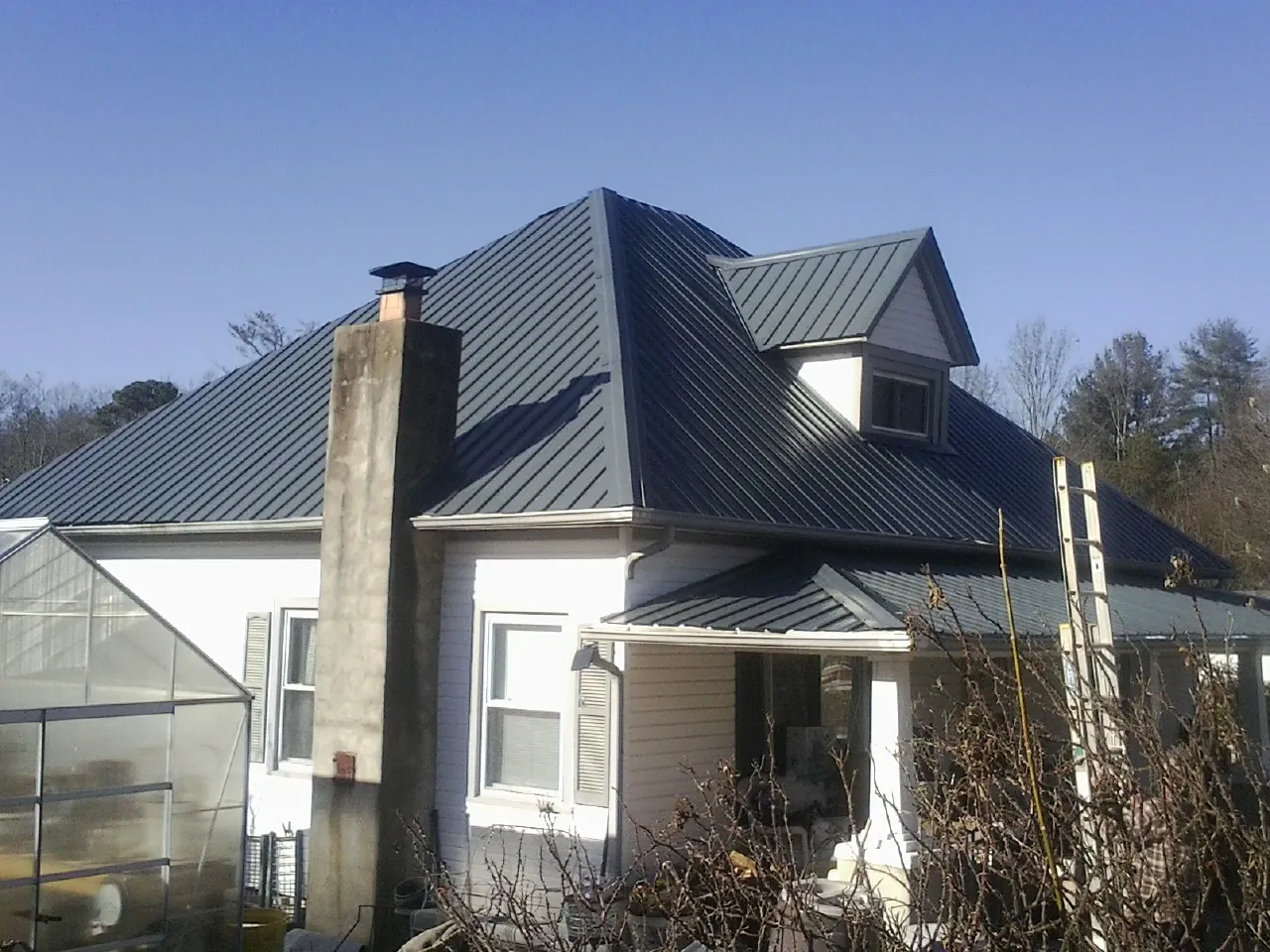 Dark blue standing seam metal roof on a white farmhouse with dormer — Slate & Tile Roof Repair by Roofing Brothers in Freeport